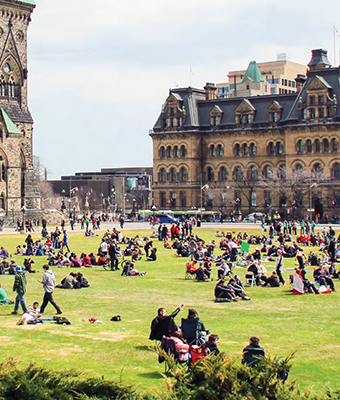 Parliament Hill with many people standing and sitting on the grass